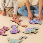 Children putting together magnetic various dinosaur puzzles on the floor.