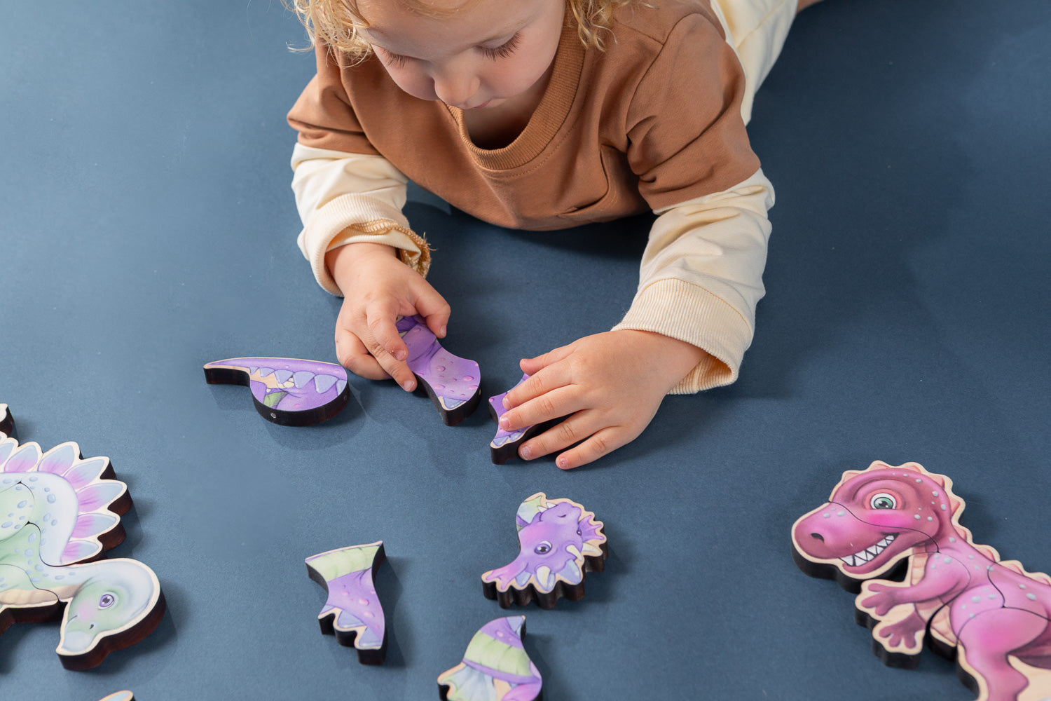 A boy assembling a magnetic wooden puzzle of a dragon.