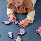 A boy assembling a magnetic wooden puzzle of a dragon.