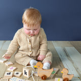 A baby playing with the learning tiles and a pull behind duck toy.