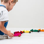 Child playing with colorful toy cars on a white surface