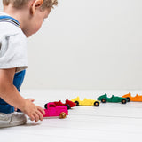 Child playing with colorful toy cars on a white surface