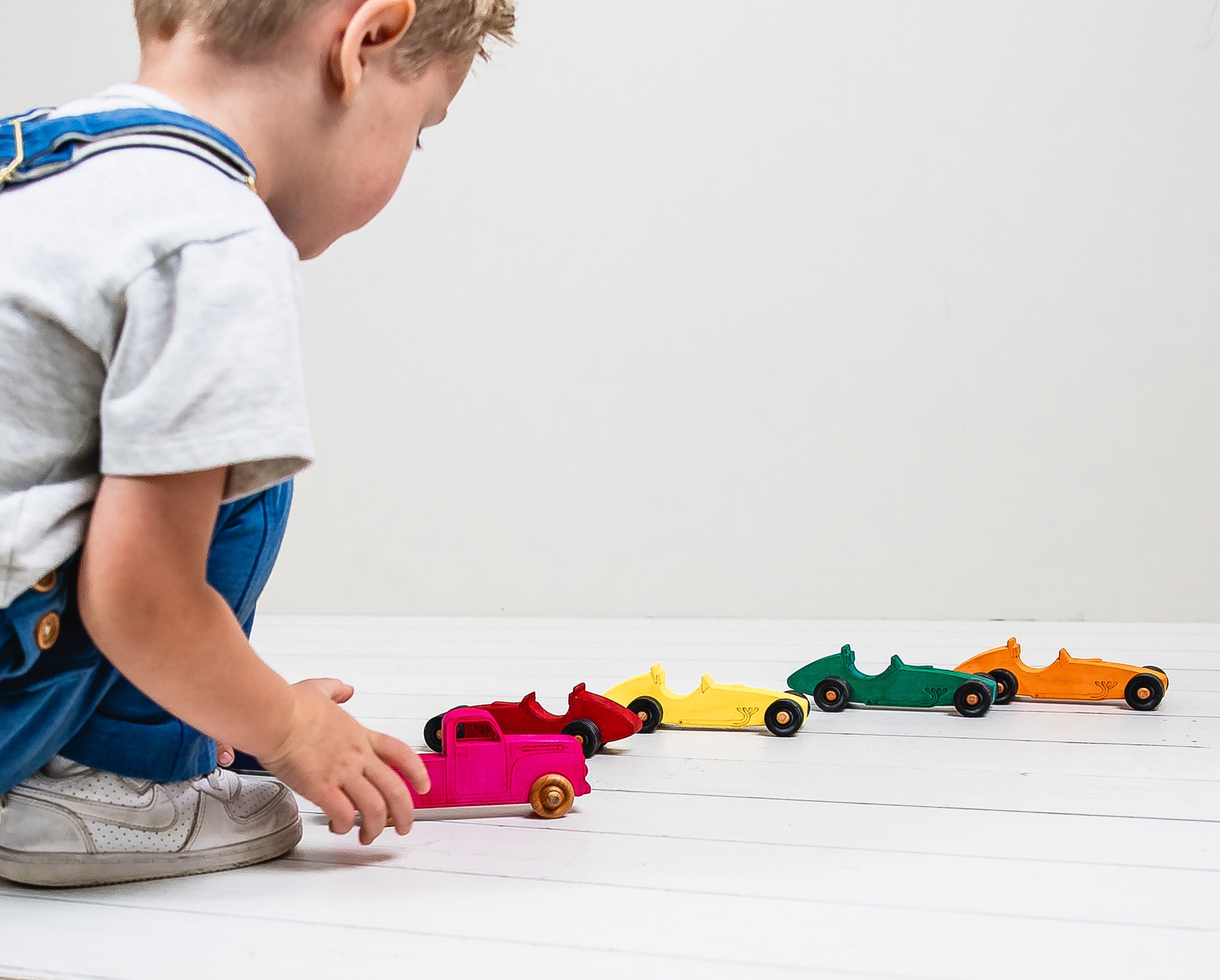 Child playing with colorful toy cars on a white surface