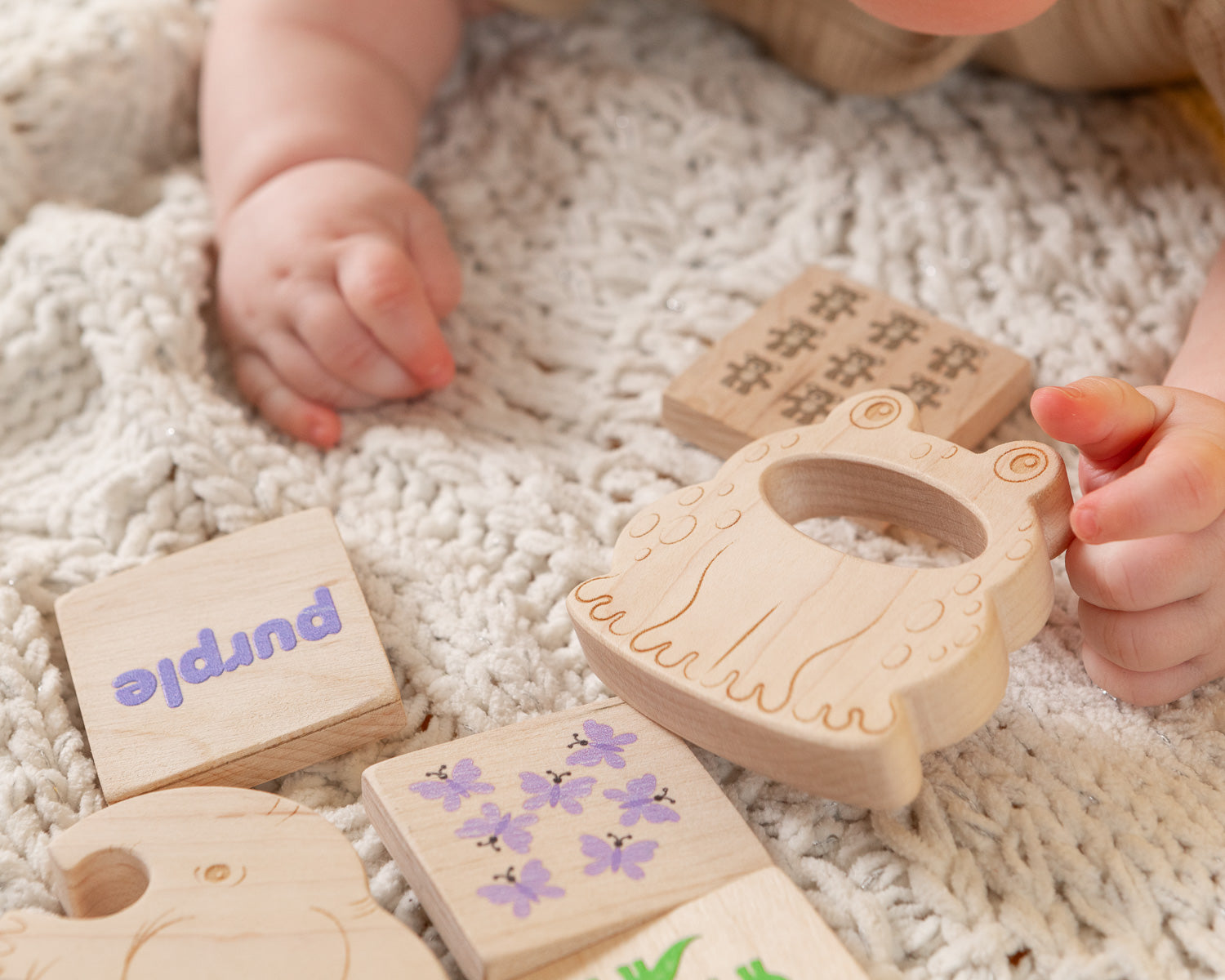 Baby's hand reaching for wooden teether and blocks.