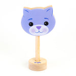 A wooden rattle with a purple cat face, a long wooden dowel for grasping and a small base with the word "cat" spelled out. 