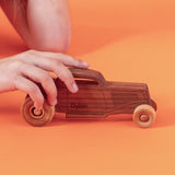 Child playing with a wooden hot rod.