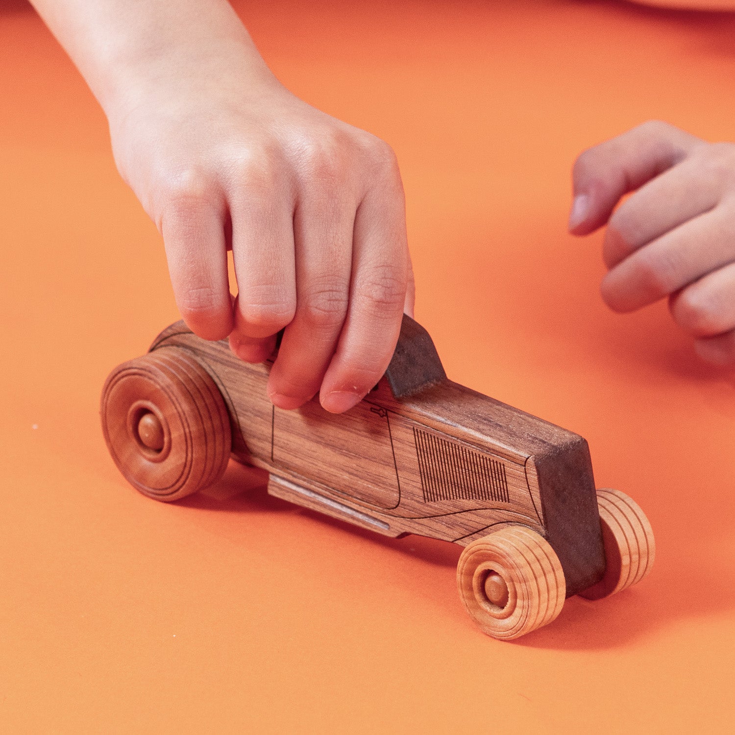 Child playing with a wooden car.