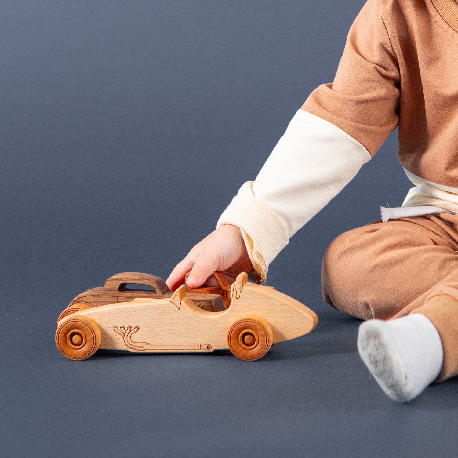Boy playing with a wooden race car.