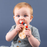A baby teething on a wood and silicone ladybug teether.