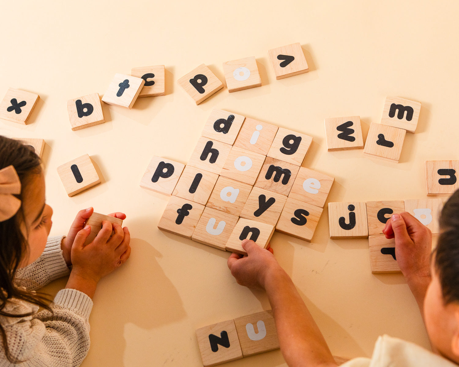 A brother and sister spelling out words with the Montessori-inspired learning tiles.