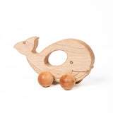 A wooden whale push toy with large textured sphere wheels.