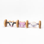 A wooden push toy featuring animal-themed designs, including a cow, pig, and sheep, with wheels for rolling.