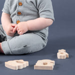 Wooden teethers lying on the ground next to a baby.