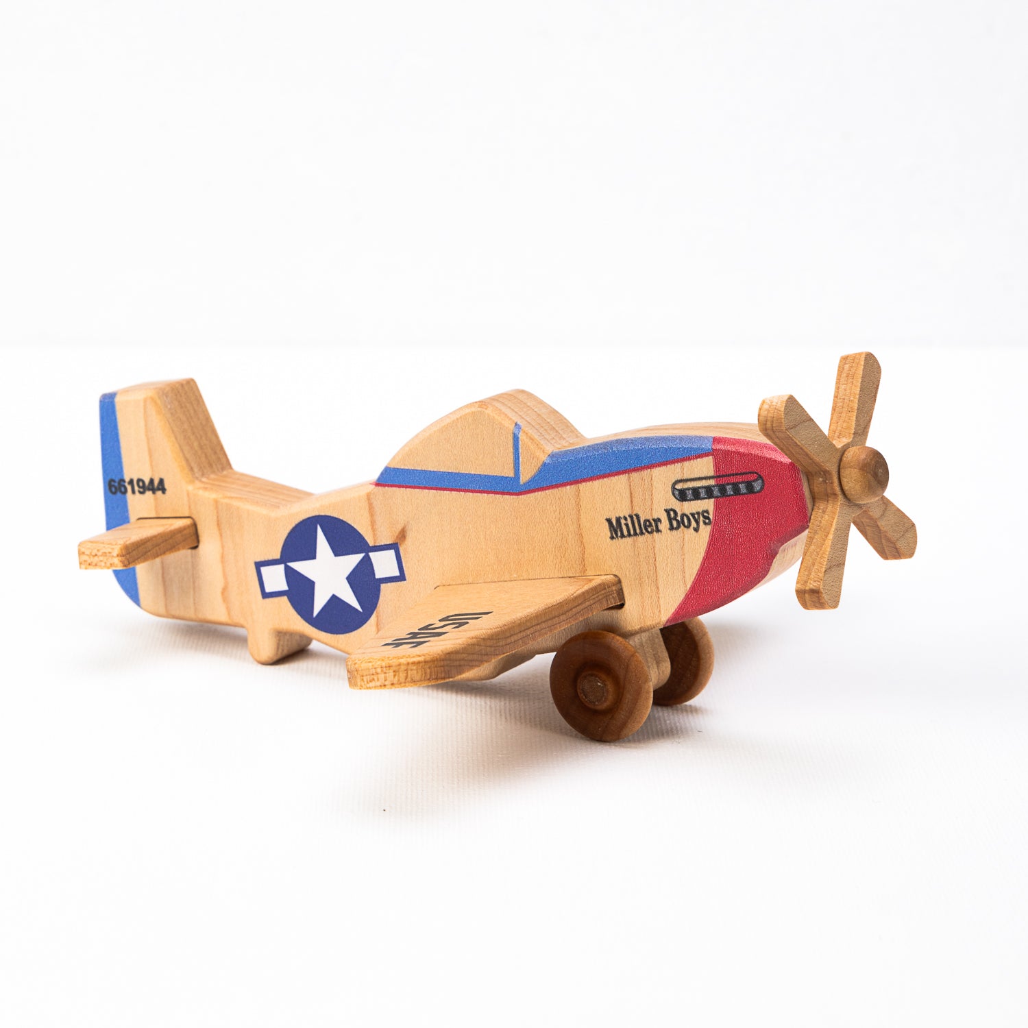 A hand-carved wooden airplane toy with a classic design, featuring a multicolored body with historical military aircraft markings, and a wooden propeller.