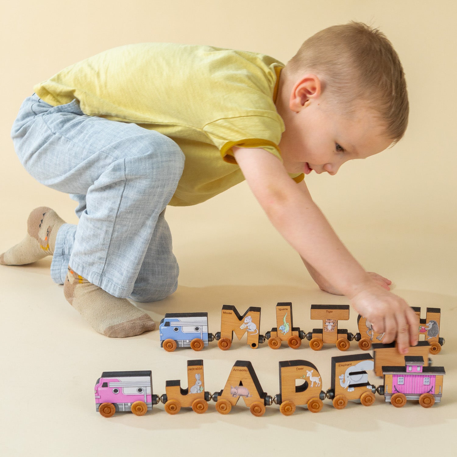 Boy playing with personalized name train that spells out his name "Mitch" and his sister's name "Jade".