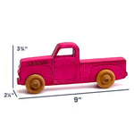 A small wooden pickup truck toy in bright pink with natural wood wheels, shown on a white background with dimension lines indicating 9 inches long, 3 3/4 inches high, and 2 1/4 inches wide.