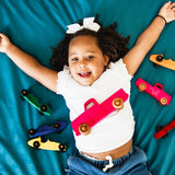 Child playing with toy cars on a blue blanket