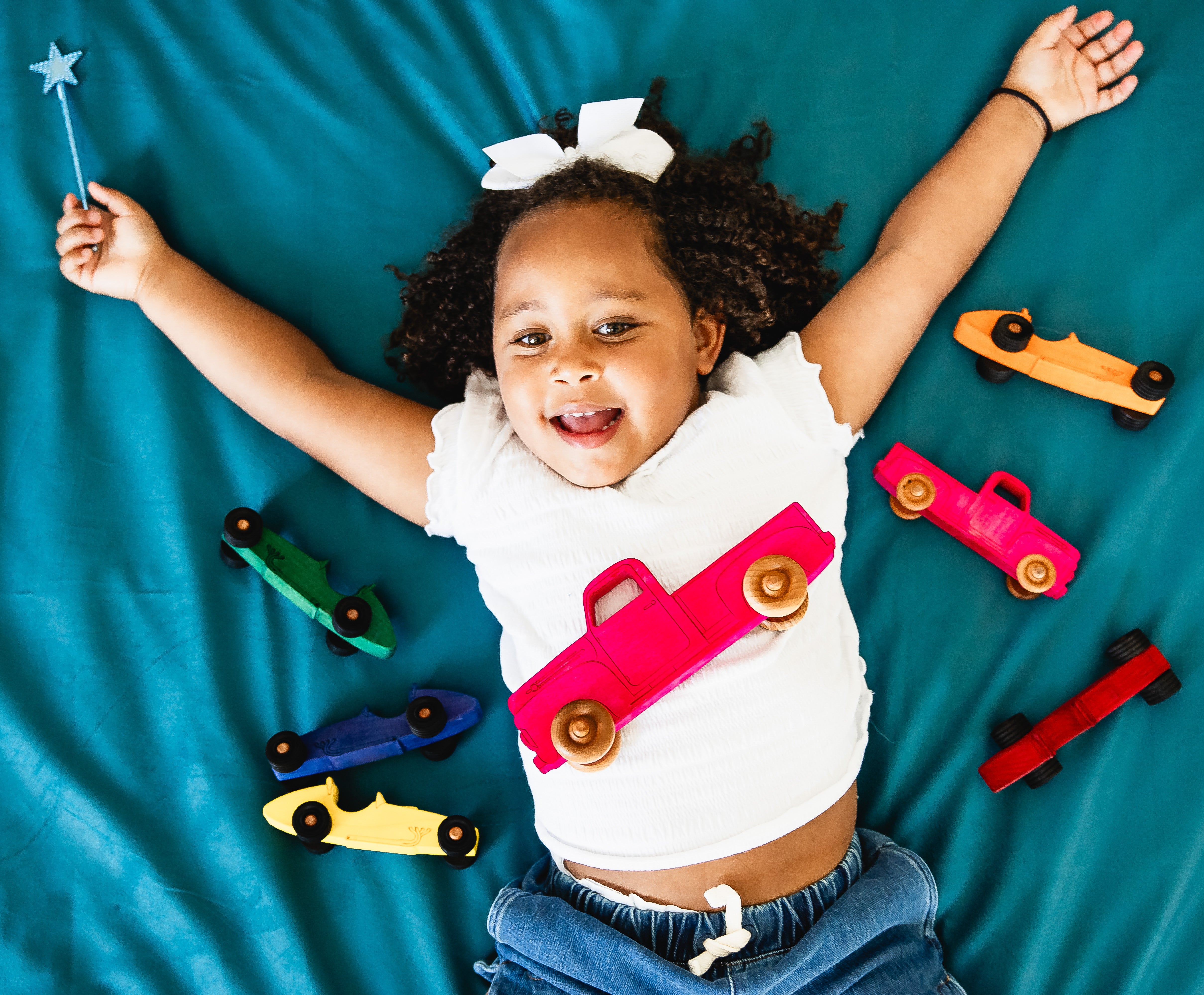 Child playing with toy cars on a blue blanket