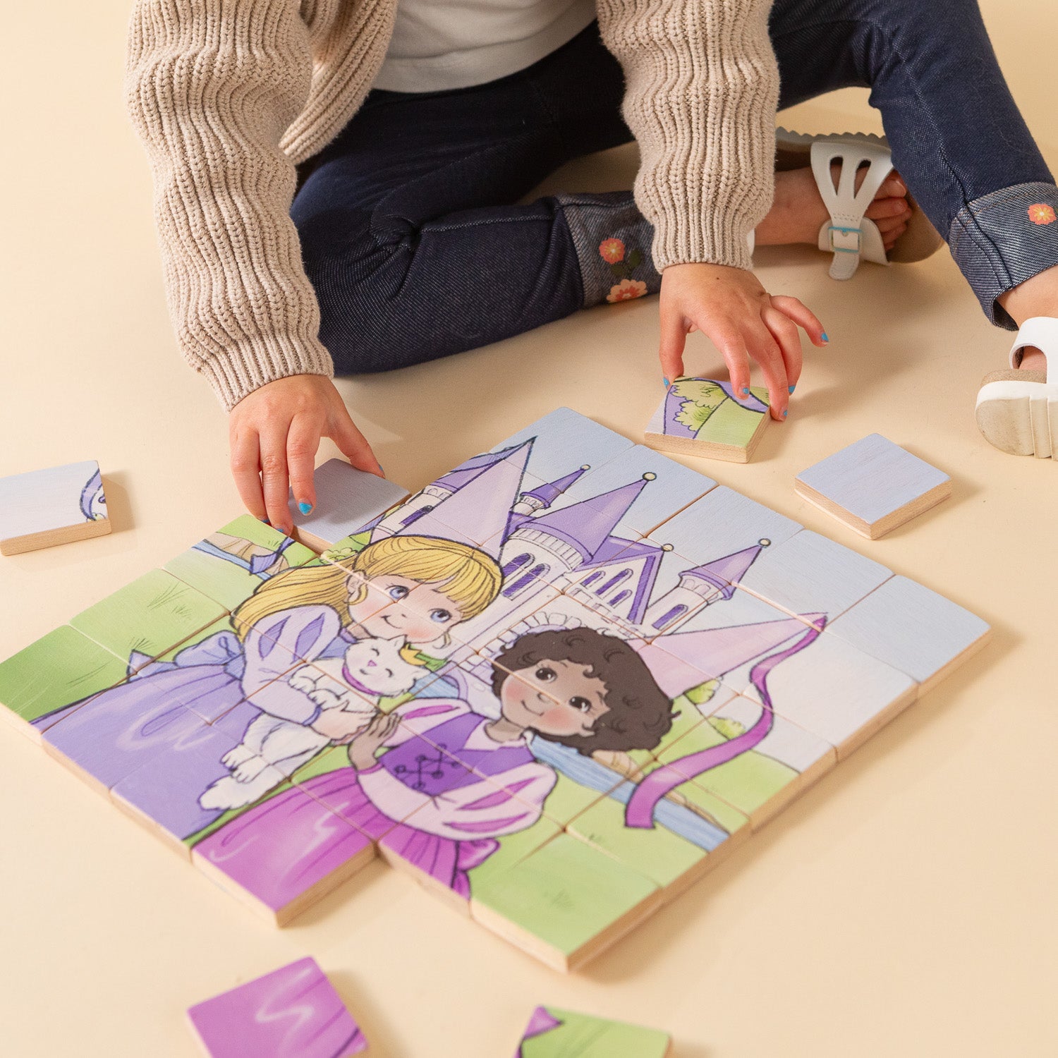 A little girl sitting on the floor putting together a wooden puzzle.