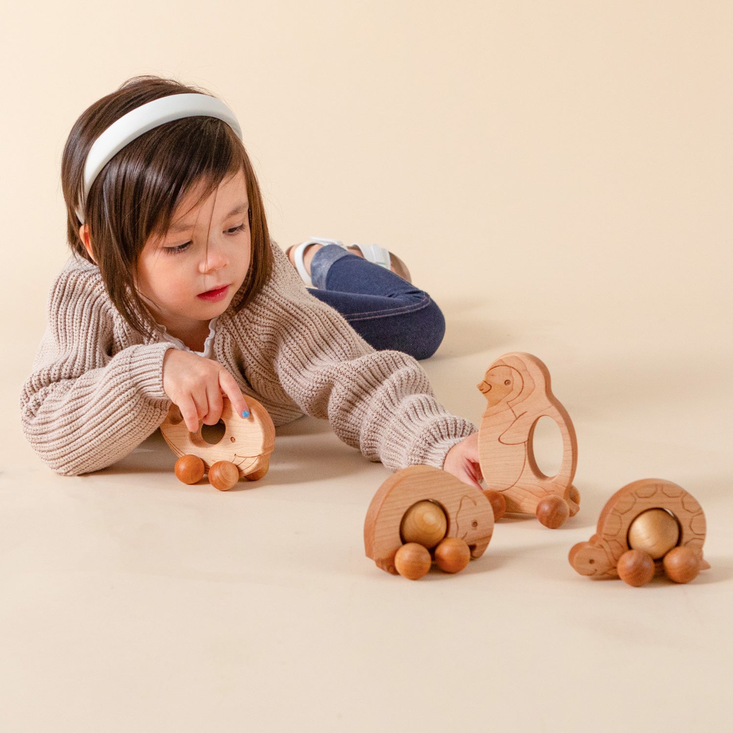 Girl playing with wooden push toys.