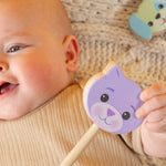 A baby holding a cat rattle.