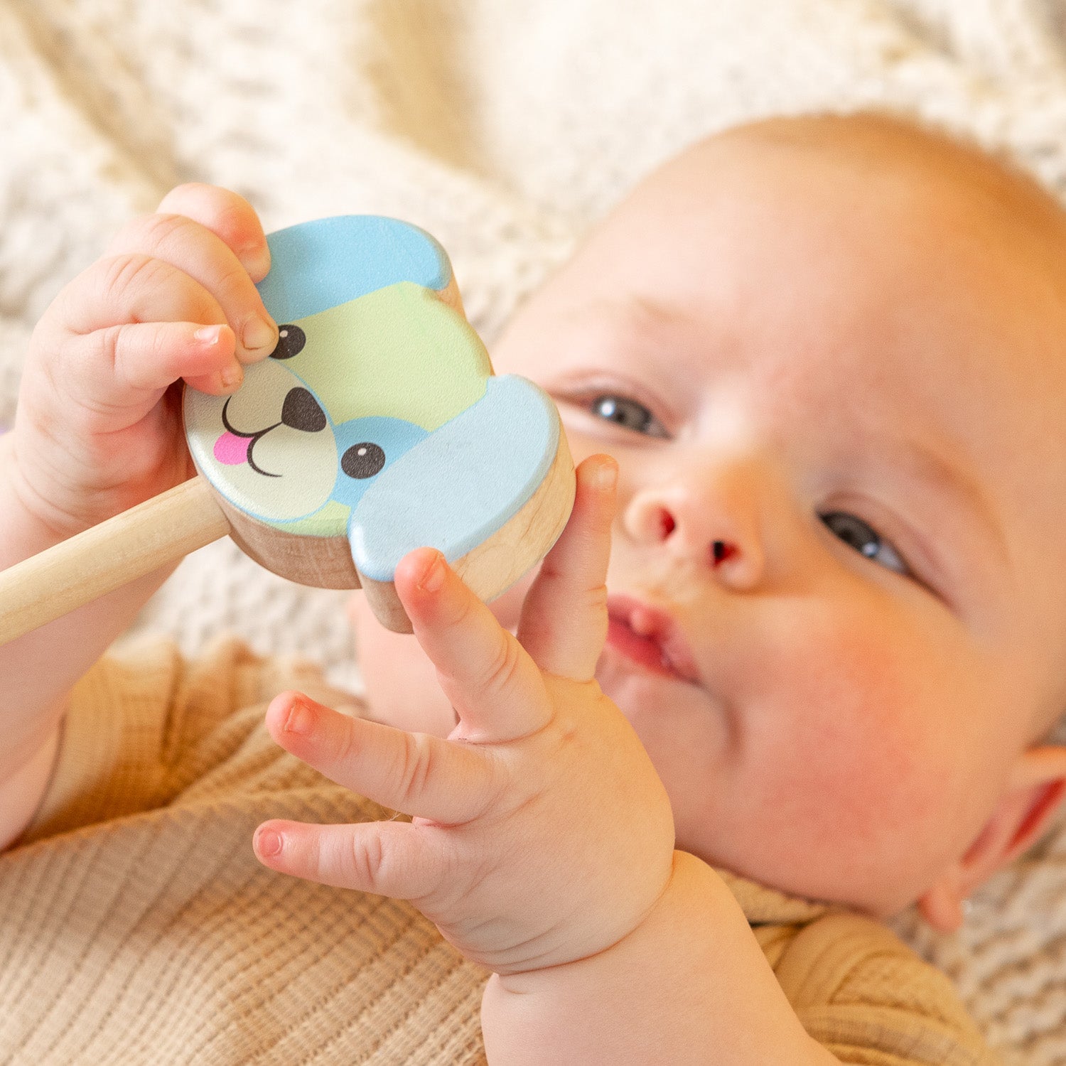A baby holding a dog rattle. 