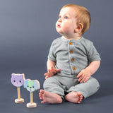 A baby sitting on the floor with a cat and a dog rattle looking up. 