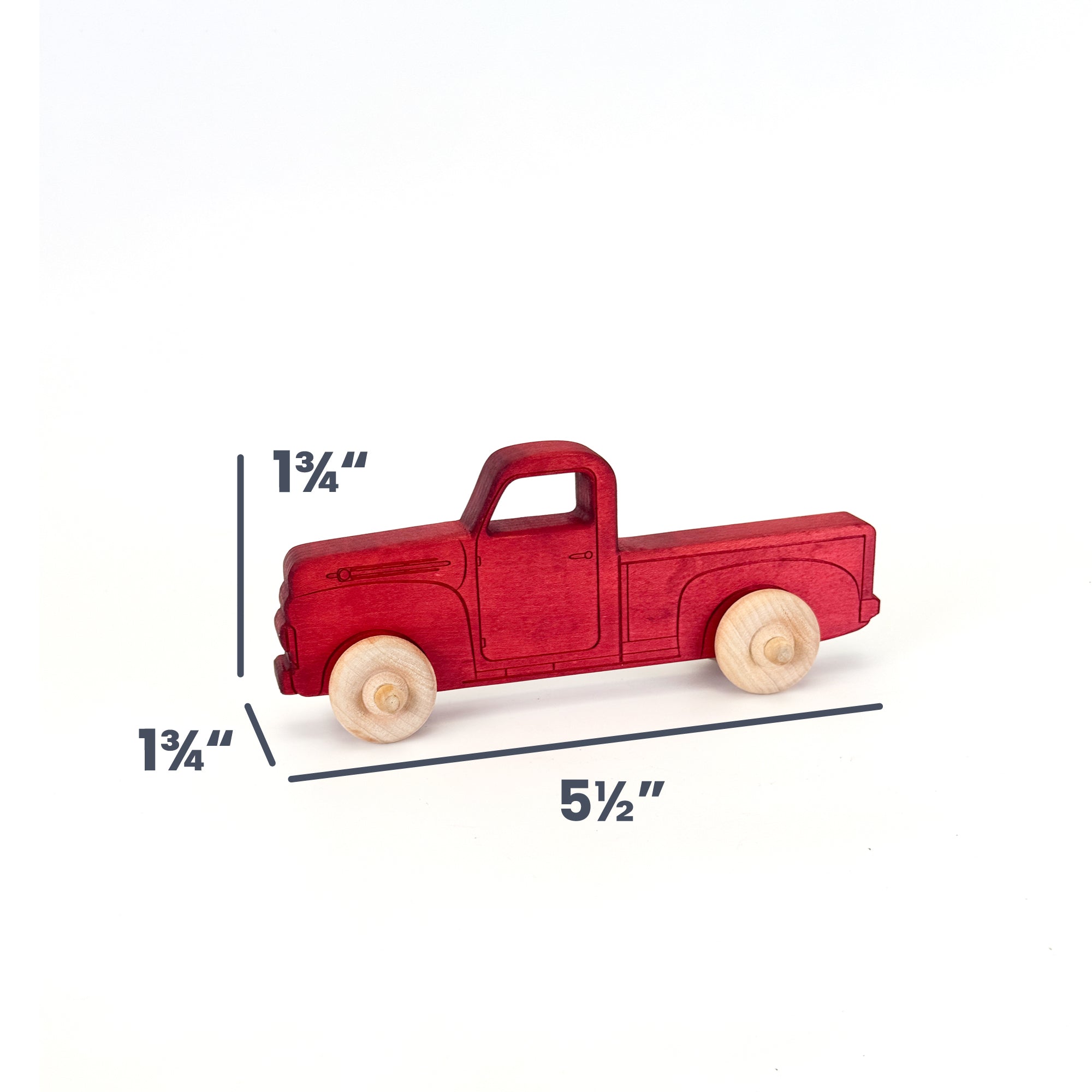 A small red wooden toy pickup truck with natural wood wheels, shown on a white background with dimension lines and text indicating 1 3/4 inches height, 1 3/4 inches width, and 5 1/2 inches length.