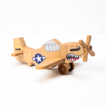 A hand-carved wooden airplane toy with a shark teeth design on the propeller and a military-style paint job.