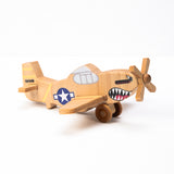 A hand-carved wooden airplane toy with a shark teeth design on the propeller and a military-style paint job.