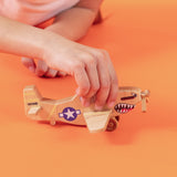 A child's hand holding a wooden P-51 Mustang WWII airplane with shark teeth.