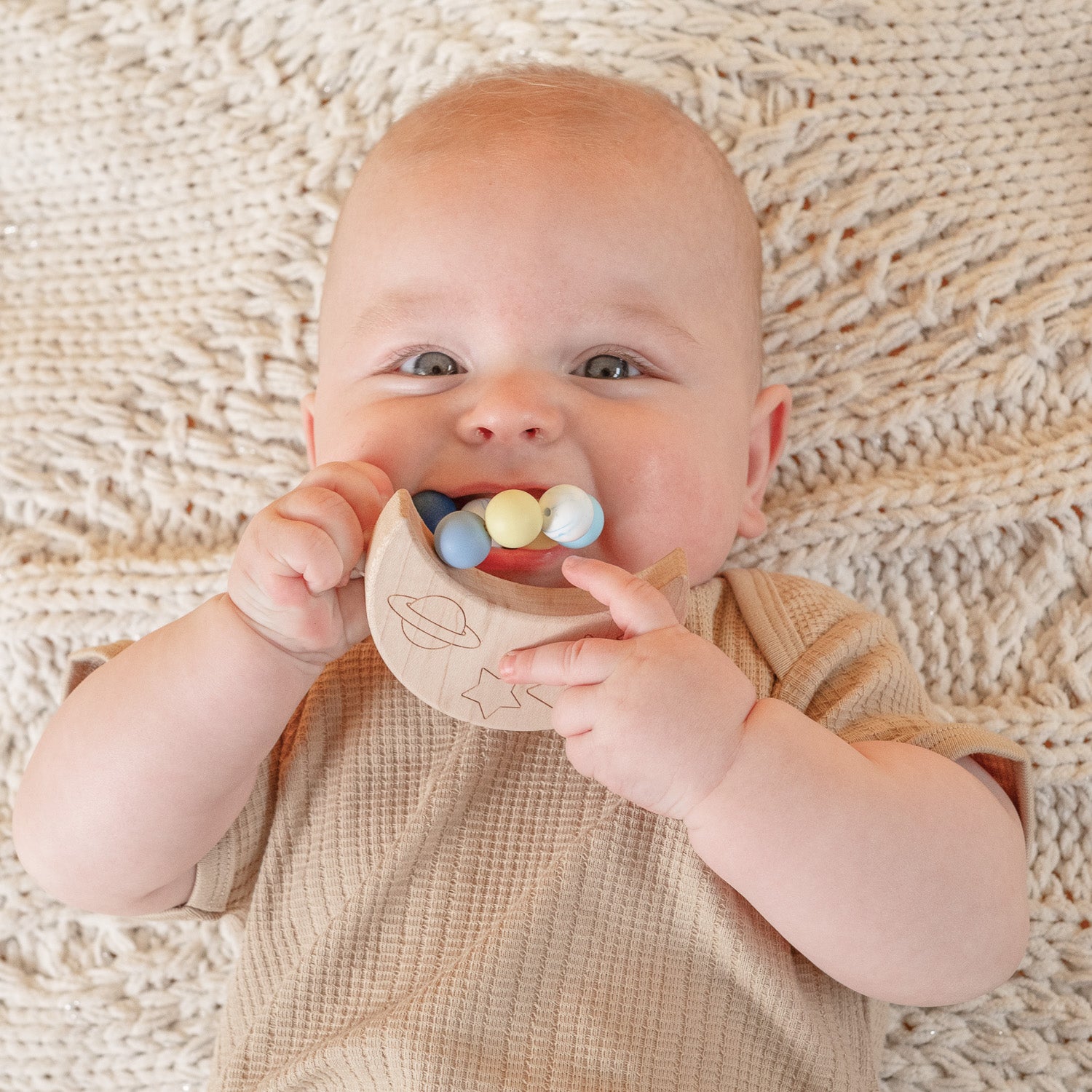 Baby lying on his back with Moon Silicone Teether in his mouth.
