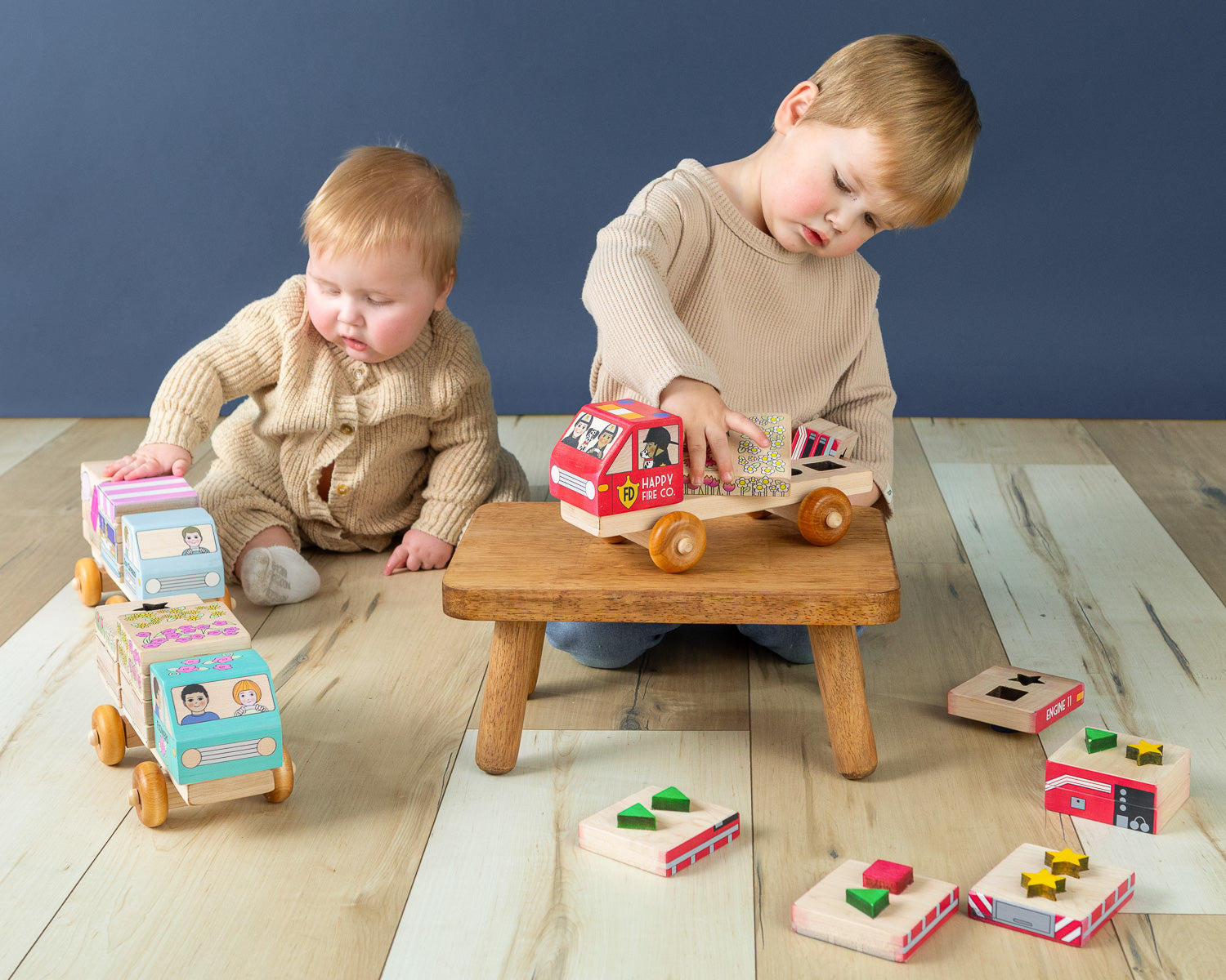 Boy and baby playing with stackable wooden trucks.