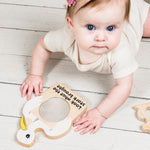 Baby playing with a wooden toy on a light wooden floor