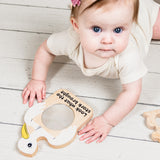 Baby playing with a wooden toy on a light wooden floor