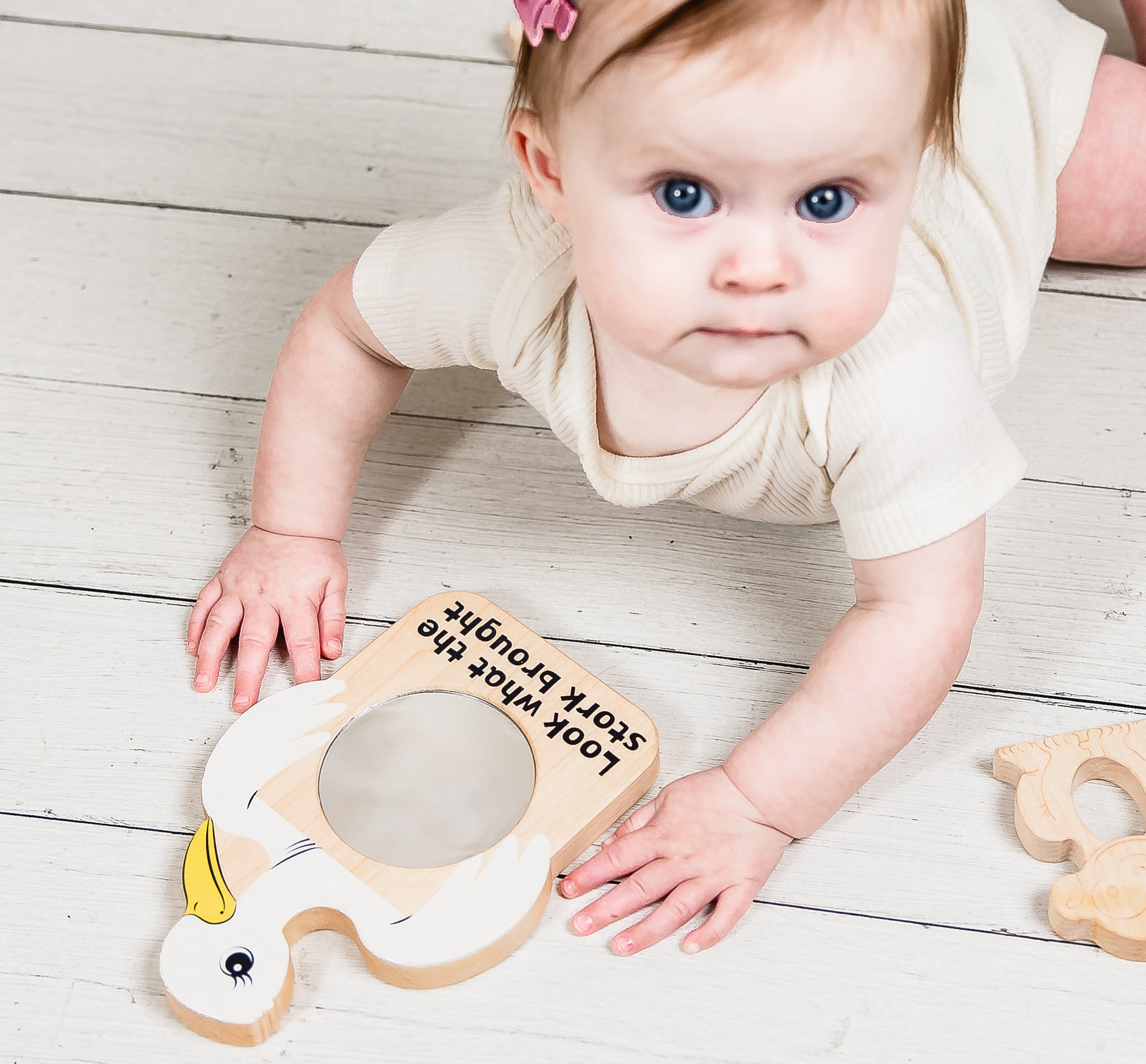 Baby playing with a wooden toy on a light wooden floor
