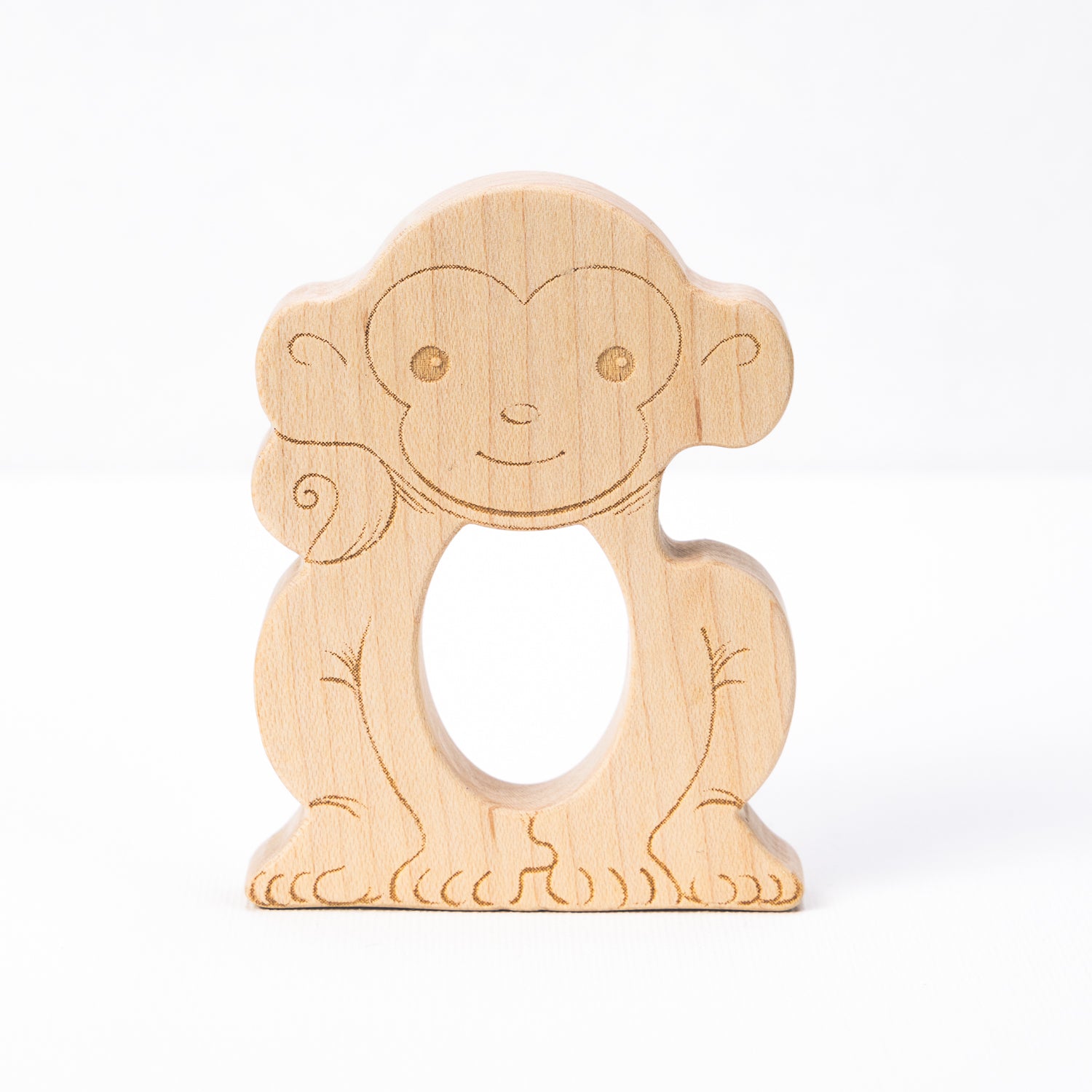 A wooden teether in the shape of a smiling monkey with a hole in the center for teething.