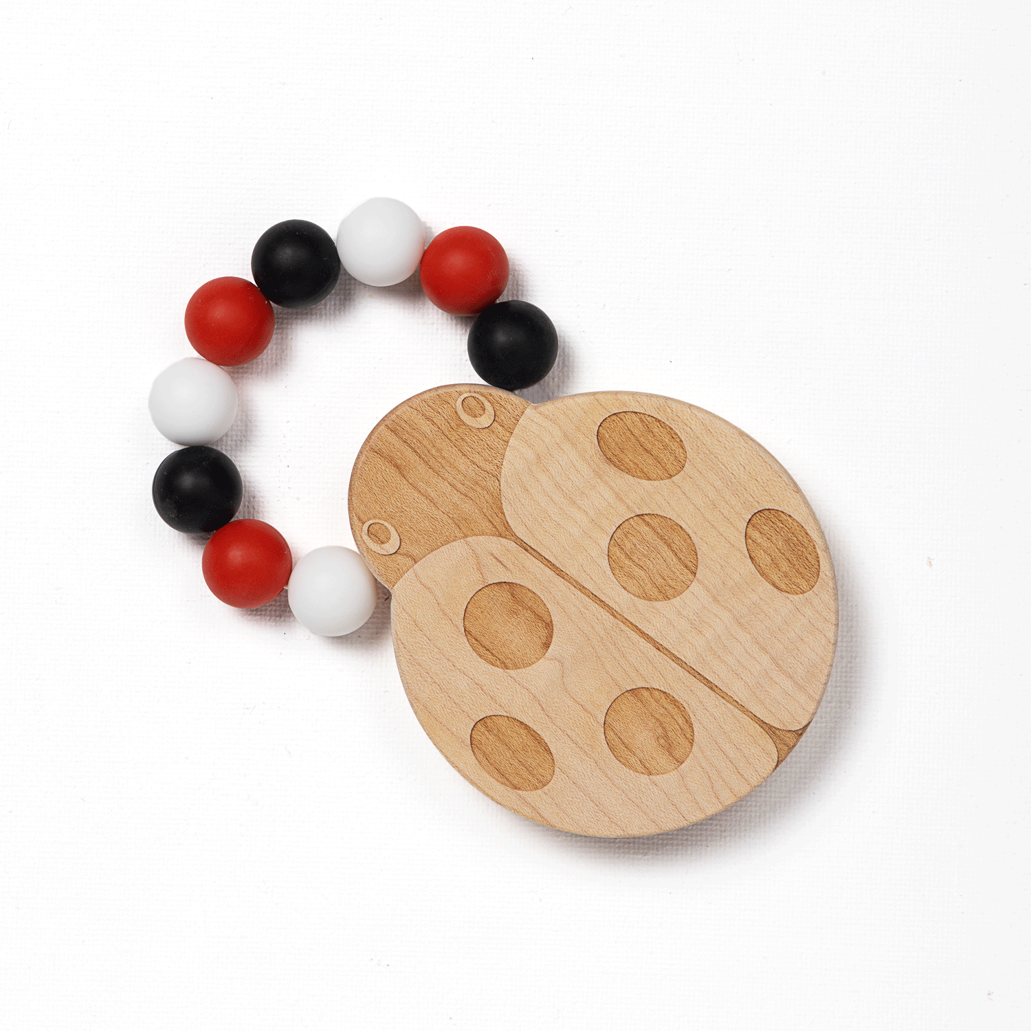 A silicone bead teether designed to look like a ladybug, with a wooden texture and red, white, and black beads attached to it.