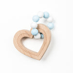A heart-shaped wooden teether with blue and white silicone beads attached to it.
