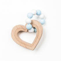 A heart-shaped wooden teether with blue and white silicone beads attached to it.