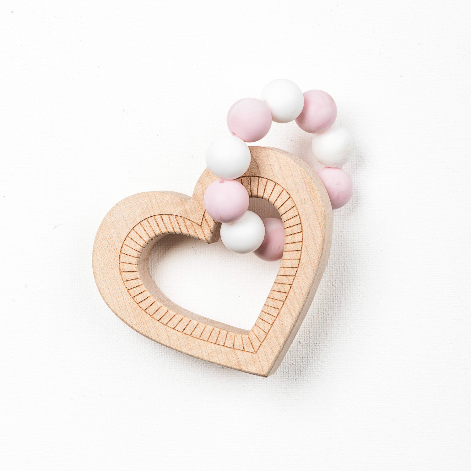 A heart-shaped teether made of silicone beads and wooden textures, primarily in pink and white colors.