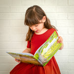 A girl in a red dress reading The Might Oak book.