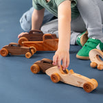 Boy playing with various wooden vehicles.