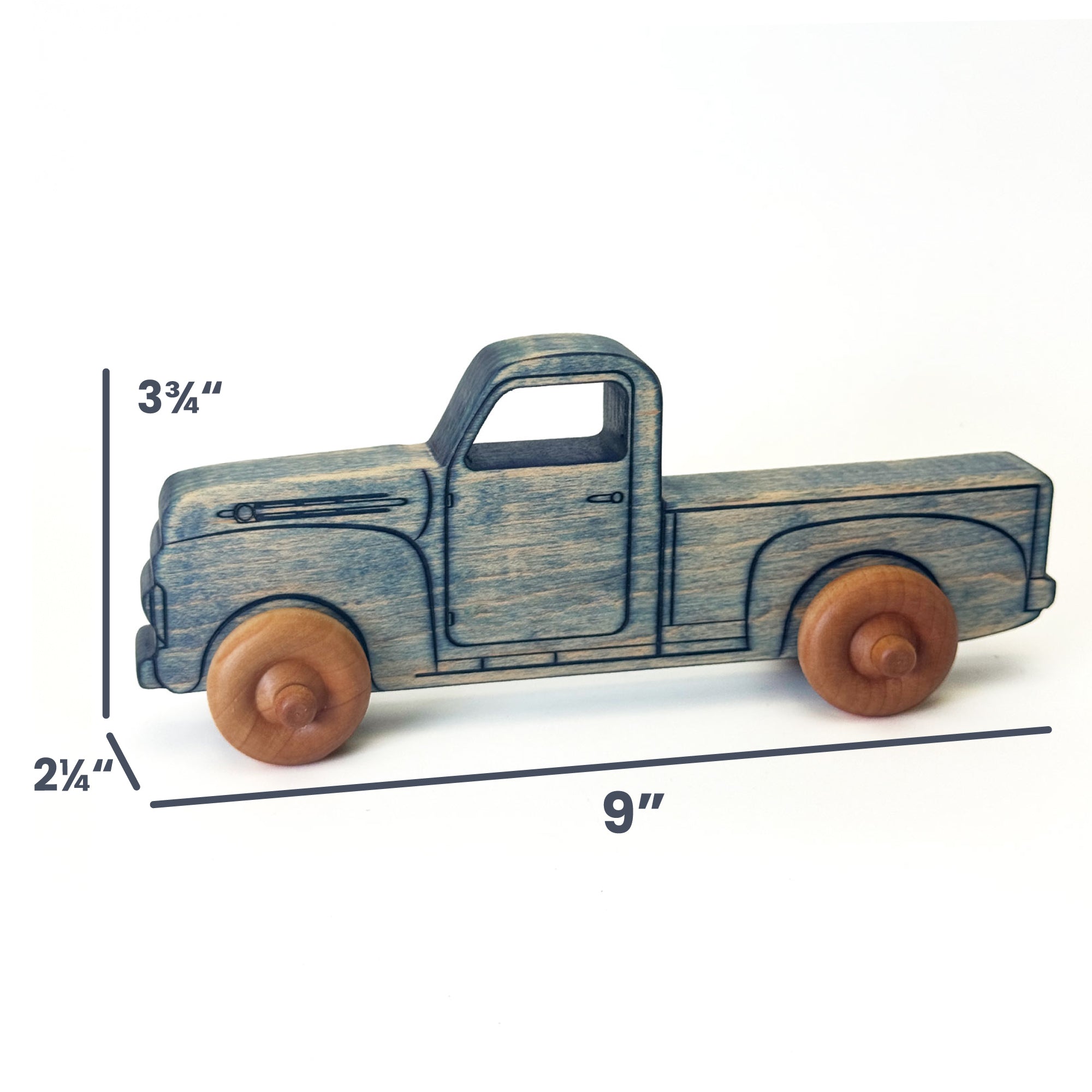A small wooden toy pickup truck with a distressed blue-gray painted finish and natural brown wood wheels, shown on a white background with dimension lines indicating 9 inches long, 3 3/4 inches high, and 2 1/4 inches deep.