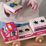 A boy playing wtih a stackable fire truck with colorful 3D puzzle shapes.