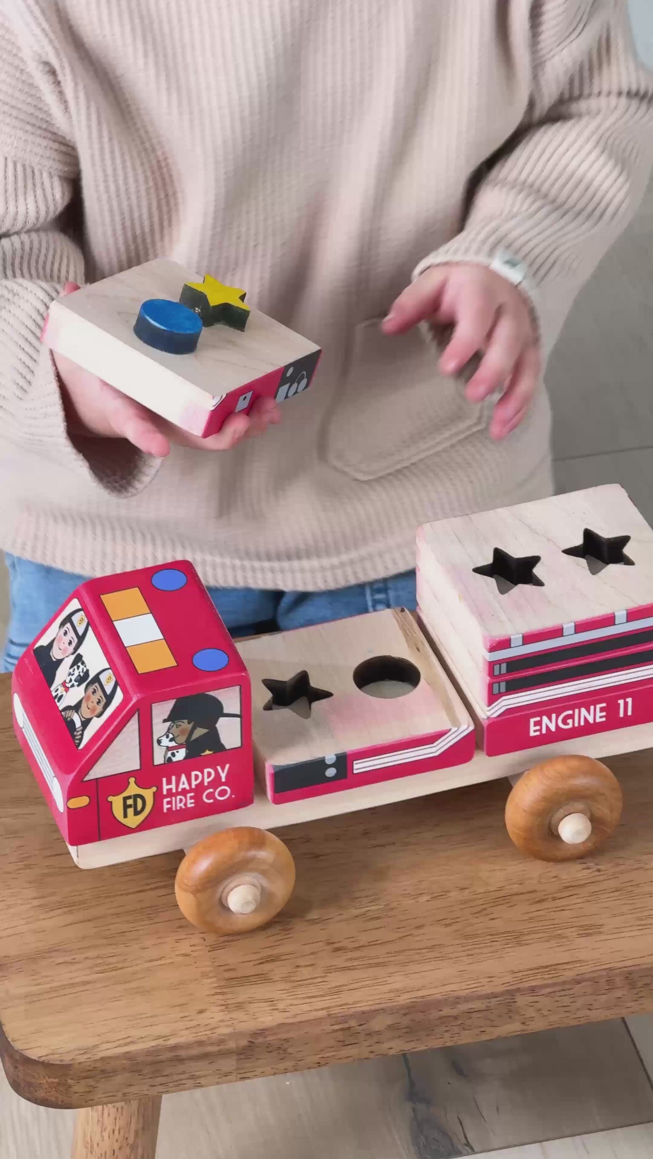 A boy playing wtih a stackable fire truck with colorful 3D puzzle shapes.