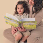 A little girl sitting on her mom's lap while she reads The Mighty Oak book.