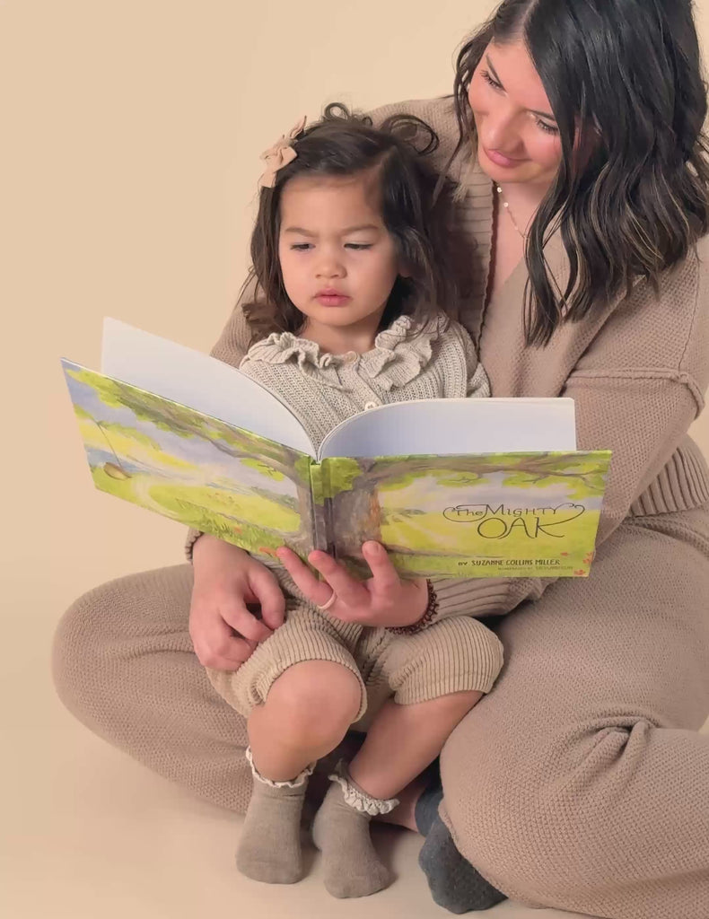 A little girl sitting on her mom's lap while she reads The Mighty Oak book.