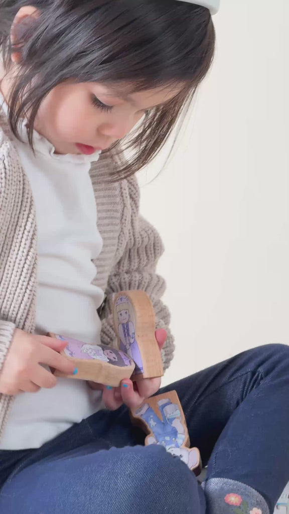 A girl playing with wooden finger puppets.