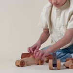 A boy playing with a wooden race car and a 1950s pickup truck.
